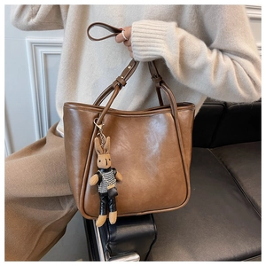 Gros plan du fourre-tout marron vintage avec texture cuir et breloque lapin mignonne