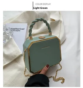 Detail of light green octagonal box bag with gold metal trim and woven handle