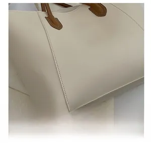 Detailed view of the precise computer stitching on the beige leather tote handbag
