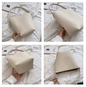 Detail view of cream bucket bag showing lychee grain texture and spacious interior