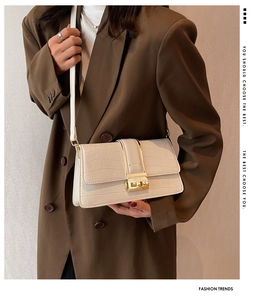 Detail of cream white crossbody bag with crocodile pattern and golden metal clasp