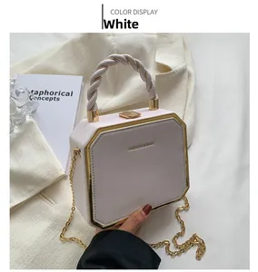 Detail of white octagonal leather handbag with gold metal trim and woven handle