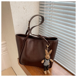 Vue latérale d'un sac cabas en simili cuir marron foncé avec un charmant lapin en peluche