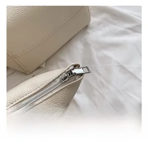 Close-up of high-quality silver zipper and lychee grain leather on a beige shoulder bag
