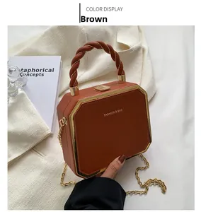 Detail of brown octagonal crossbody bag with woven handle and gold chain strap