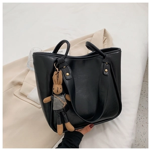 Détail du sac cabas noir en similicuir avec garniture dorée et pendentif lapin élégant