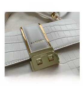 Close-up of white crocodile pattern crossbody bag with golden metal buckle and leather strap