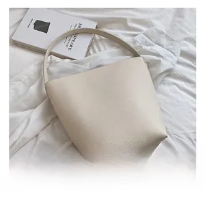 Detailed close-up of a beige lychee pattern leather bucket bag on a white textured background