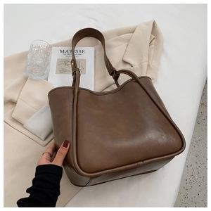Détail d'un sac cabas marron foncé avec bandoulières nouées et texture en cuir mat