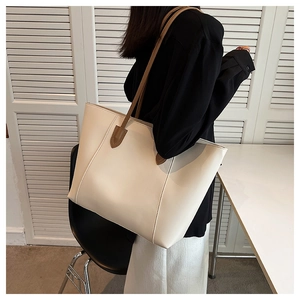 Detail of minimalist cream tote bag with brown straps and vertical stitching detail