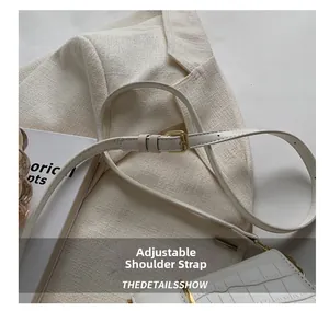 Macro view of adjustable shoulder strap and gold buckle on cream croc-embossed crossbody bag