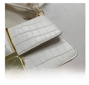 Detail of white crocodile texture leather bag with gold buckle and neat stitching