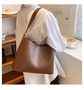 Brown leather tote bag for women showing spacious capacity and side view on a model