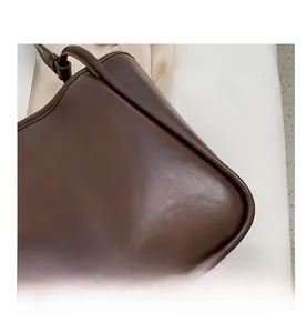Gros plan détaillé des coutures et des finitions métalliques du sac cabas marron