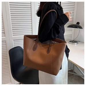 Detail of a large brown tote bag showing contrast stitching and premium leather texture