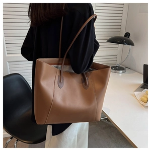 Brown large capacity leather tote bag with fine stitching shown in an office setting
