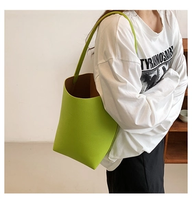Close-up of bright green litchi-textured bucket bag with wide shoulder strap