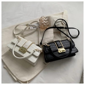 Close-up of crocodile pattern leather flap bag featuring a gold rotation lock with engraving