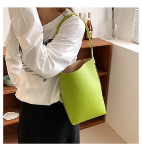 Grass green leather crossbody bag with pebbled texture shown on a model in a bright room