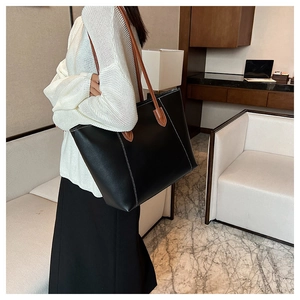 Detail of black commute tote bag with brown leather straps and white contrast stitching