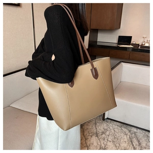 Detailed view of khaki leather tote bag featuring brown long shoulder straps and stitching