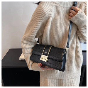 Detail of black crocodile texture crossbody bag featuring a gold clasp and fashion text