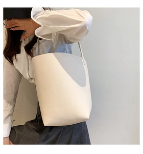 Detailed macro of white bucket tote bag featuring pebbled leather texture and slim strap