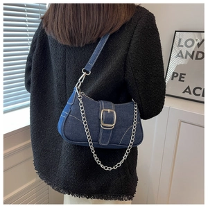Dettaglio borsa a spalla in denim blu con catena argentata e fibbia in metallo