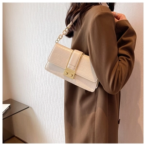 Detail of cream crossbody bag with croc-embossed texture and gold square lock buckle