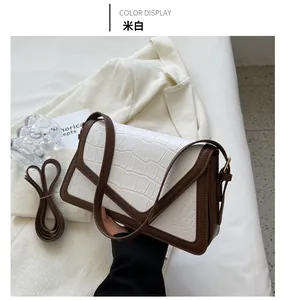 Detail of cream white faux crocodile leather shoulder bag with brown trim and strap