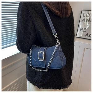 Dettaglio borsa a sella in denim vintage con catena in metallo e fibbia argento sul modello