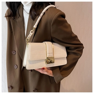 Detail of white crocodile embossed crossbody bag with gold buckle and chain strap