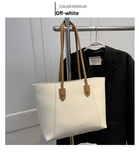 Detail of cream tote bag with contrast brown straps and V-shaped stitching design