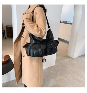 Detail of black multi-pocket oversized hobo bag showing faux leather texture and buckles