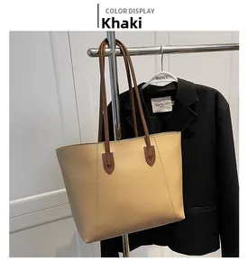 Detail of khaki leather tote bag with V-shaped stitching and dark brown handles