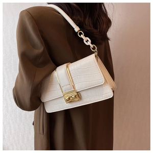 Close-up of white croc-embossed crossbody bag with gold lock and metal chain strap