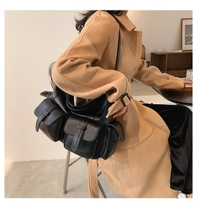 Detail of black multi-pocket shoulder bag with matte leather texture on a model