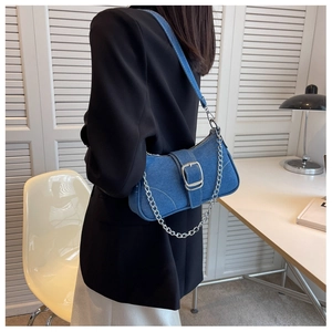 Borsa sottobraccio in denim blu con catena d'argento indossata da modella in interno