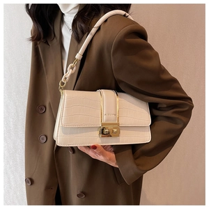 Detail of cream crossbody bag with crocodile texture and gold FASHION twist lock