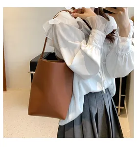 Mirror selfie showing the scale and fit of this minimalist brown leather bucket bag for women