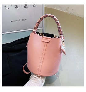 Detail of pink lychee leather bucket bag with a silk scarf handle and brand logo