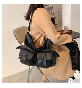Detail of the multi-pocket structure and soft black leather texture on this tote bag
