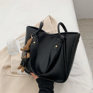 Cabas noir minimaliste en cuir lisse avec rivets dorés et charmant pendentif lapin