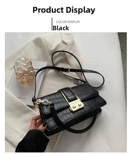 Close-up of black croc-effect crossbody bag with gold fashion buckle and hardware