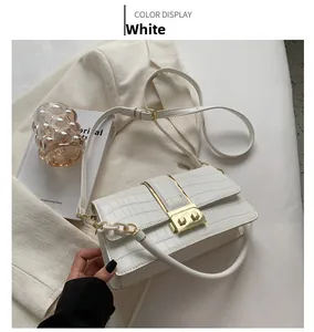 Detail of white crocodile embossed leather crossbody bag with golden metal buckle