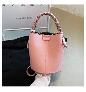 Detailed macro of pink lychee leather bucket bag featuring a silk scarf-wrapped handle