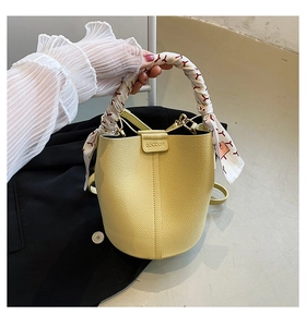 Detail of yellow lychee leather bucket bag with printed silk scarf wrapped on handle