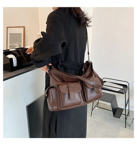 Deep brown utilitarian crossbody bag with multiple pockets shown on model for scale