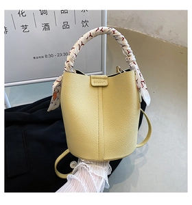 Detail of light yellow lychee pattern leather bucket bag with silk scarf handle