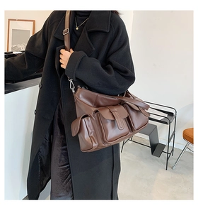Detail of dark brown leather tote bag with three front utility pockets and silver buckles